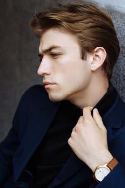 Şehrin üzerinde el, altın bilek watch.pensive gri background.watch üzerinde mavi elbiseli çekici bir genç adam portresi