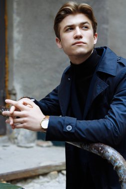 Şehrin üzerinde el, altın bilek watch.pensive gri background.watch üzerinde mavi elbiseli çekici bir genç adam portresi