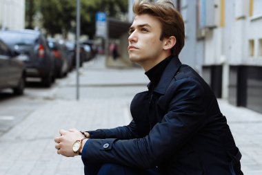 Şehrin üzerinde el, altın bilek watch.pensive gri background.watch üzerinde mavi elbiseli çekici bir genç adam portresi