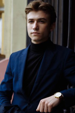 Şehrin üzerinde el, altın bilek watch.pensive gri background.watch üzerinde mavi elbiseli çekici bir genç adam portresi