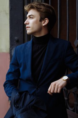 Şehrin üzerinde el, altın bilek watch.pensive gri background.watch üzerinde mavi elbiseli çekici bir genç adam portresi