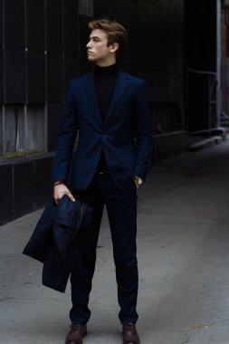 Mavi bir takım elbise, ceket, kentin yakışıklı, çekici, Genç bir adam portresi. dalgın ve üzgün, bekliyor. iş adamı. yandan izle