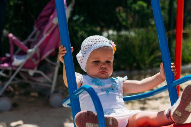 üzgün, küçük kız bir salıncak, yaz güneş ve ısı sürme bir beyaz elbise ve şapka. Bahçesi. çocukluk, serenity. olumsuz duygular, öfke