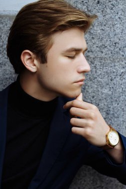 Şehrin üzerinde el, altın bilek watch.pensive gri background.watch üzerinde mavi elbiseli çekici bir genç adam profile.portrait adam