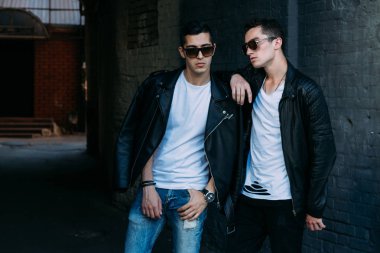 güzel ve çekici adam şehirde ayakta, poz. siyah deri kurta, beyaz T-shirt, kot pantolon ve beyaz ayakkabı giymiş. ayna Binası yakınında. siyah gözlük şehirde dolaşmak. iletişim. Toplantı arkadaşlar.