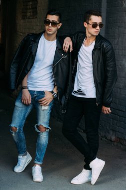 güzel ve çekici adam şehirde ayakta, poz. siyah deri kurta, beyaz T-shirt, kot pantolon ve beyaz ayakkabı giymiş. ayna Binası yakınında. siyah gözlük şehirde dolaşmak. iletişim. Toplantı arkadaşlar.