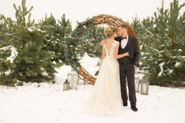 bir kış orman, bir daire dekore edilmiş üzüm, beyaz bir elbise ve suit.bride ve damat ile çiçek çerçevede birkaç bir erkek ve bir kadın duruyor. Ladin buket. kızı geri görüntülemek