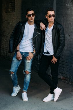 güzel ve çekici adam şehirde ayakta, poz. bir siyah deri ceket, beyaz T-shirt, kot pantolon ve beyaz ayakkabı giymiş. ayna Binası yakınında. siyah gözlük şehirde dolaşmak. iletişim. Toplantı arkadaşlar.