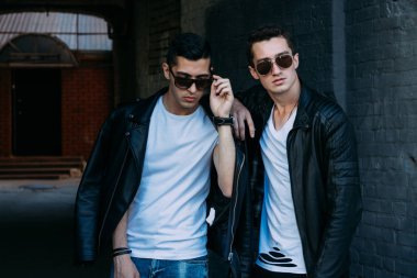 güzel ve çekici adam şehirde ayakta, poz. bir siyah deri ceket, beyaz T-shirt, kot pantolon ve beyaz ayakkabı giymiş. ayna Binası yakınında. siyah gözlük şehirde dolaşmak. iletişim. Toplantı arkadaşlar.