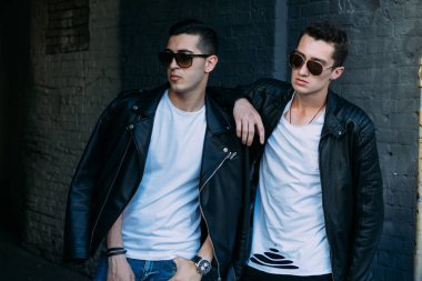 güzel ve çekici adam şehirde ayakta, poz. bir siyah deri ceket, beyaz T-shirt, kot pantolon ve beyaz ayakkabı giymiş. ayna Binası yakınında. siyah gözlük şehirde dolaşmak. iletişim. Toplantı arkadaşlar.