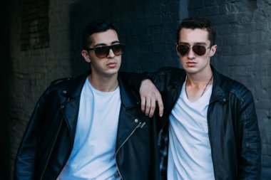 güzel ve çekici adam şehirde ayakta, poz. bir siyah deri ceket, beyaz T-shirt, kot pantolon ve beyaz ayakkabı giymiş. ayna Binası yakınında. siyah gözlük şehirde dolaşmak. iletişim. Toplantı arkadaşlar.