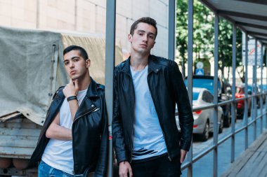 güzel ve çekici adam şehirde ayakta, poz. bir siyah deri ceket, beyaz T-shirt, kot pantolon ve beyaz ayakkabı giymiş. ayna Binası yakınında. siyah gözlük şehirde dolaşmak. iletişim. Toplantı arkadaşlar.