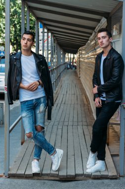güzel ve çekici adam şehirde ayakta, poz. bir siyah deri ceket, beyaz T-shirt, kot pantolon ve beyaz ayakkabı giymiş. ayna Binası yakınında. siyah gözlük şehirde dolaşmak. iletişim. Toplantı arkadaşlar.