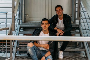 güzel ve çekici adam şehirde ayakta, poz. bir siyah deri ceket, beyaz T-shirt, kot pantolon ve beyaz ayakkabı giymiş. ayna Binası yakınında. siyah gözlük şehirde dolaşmak. iletişim. Toplantı arkadaşlar.