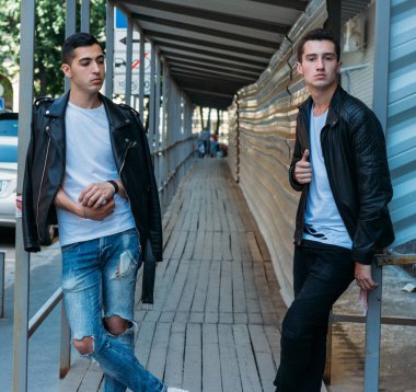güzel ve çekici adam şehirde ayakta, poz. bir siyah deri ceket, beyaz T-shirt, kot pantolon ve beyaz ayakkabı giymiş. ayna Binası yakınında. şehir etrafında yürümek. iletişim. Toplantı arkadaşlar.