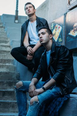 güzel ve çekici adam şehirde ayakta, poz. bir siyah deri ceket, beyaz T-shirt, kot pantolon ve beyaz ayakkabı giymiş. ayna Binası yakınında. şehir etrafında yürümek. iletişim. Toplantı arkadaşlar.