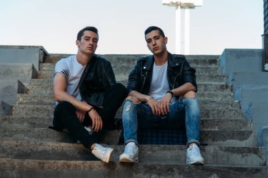 güzel ve çekici adam şehirde ayakta, poz. bir siyah deri ceket, beyaz T-shirt, kot pantolon ve beyaz ayakkabı giymiş. ayna Binası yakınında. şehir etrafında yürümek. iletişim. Toplantı arkadaşlar.