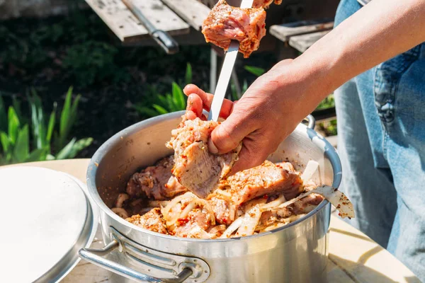 一个人把生肉串在金属烤肉串上 放在火上煮 烤小鱼烤肉串 串上的肉放在一个白色的托盘上 用洋葱和辣椒煮肉 — 图库照片