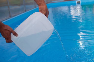 Erkekler eller hafif sıvı plastik bir tank bir havuza su içine dökün. kimyasal su arıtma, alkali dengesi, sağlıksız conditions.disinfection ve yüzme için hazırlık. Havuz Bakımı