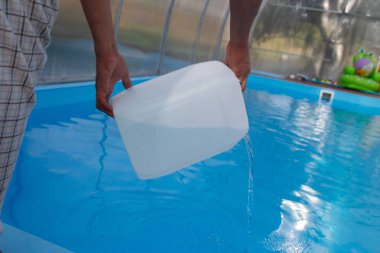 Erkekler eller hafif sıvı plastik bir tank bir havuza su içine dökün. kimyasal su arıtma, alkali dengesi, sağlıksız conditions.disinfection ve yüzme için hazırlık. Havuz Bakımı