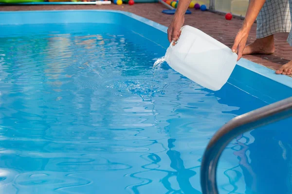 Erkekler eller hafif sıvı plastik bir tank bir havuza su içine dökün. kimyasal su arıtma, alkali dengesi, sağlıksız conditions.disinfection ve yüzme için hazırlık. Havuz Bakımı