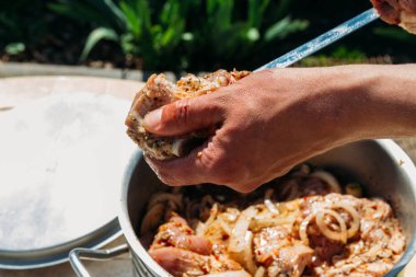 bir adam için ateşe cook metal bir şiş üzerinde çiğ et parçalarını dizeleri. Barbekü. soğan ve biber et pişirmek.