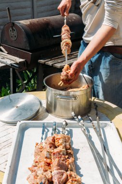 bir adam için ateşe cook metal bir şiş üzerinde çiğ et parçalarını dizeleri. Barbekü. soğan ve biber et pişirmek.