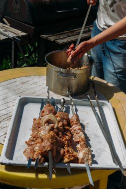 bir adam için ateşe cook metal bir şiş üzerinde çiğ et parçalarını dizeleri. Barbekü. soğan ve biber et pişirmek.