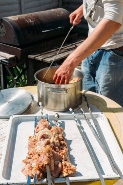 bir adam için ateşe cook metal bir şiş üzerinde çiğ et parçalarını dizeleri. Barbekü. soğan ve biber et pişirmek.