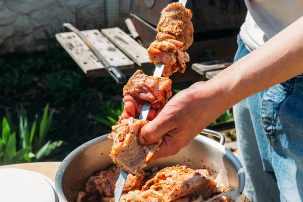 Bir adam için ateşe cook metal bir şiş üzerinde çiğ et parçalarını dizeleri. Barbekü. soğan ve biber et pişirmek. — Stok fotoğraf