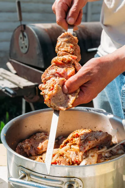 Bir adam için ateşe cook metal bir şiş üzerinde çiğ et parçalarını dizeleri. Barbekü. soğan ve biber et pişirmek. — Stok fotoğraf