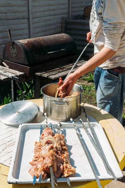 Bir adam için ateşe cook metal bir şiş üzerinde çiğ et parçalarını dizeleri. Barbekü. soğan ve biber et pişirmek. — Stok fotoğraf