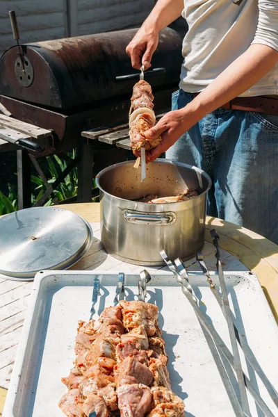 Bir adam için ateşe cook metal bir şiş üzerinde çiğ et parçalarını dizeleri. Barbekü. soğan ve biber et pişirmek. — Stok fotoğraf