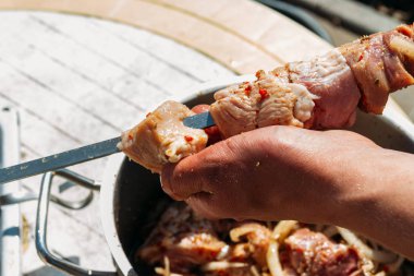 bir adam için ateşe cook metal bir şiş üzerinde çiğ et parçalarını dizeleri. Barbekü. soğan ve biber et pişirmek.