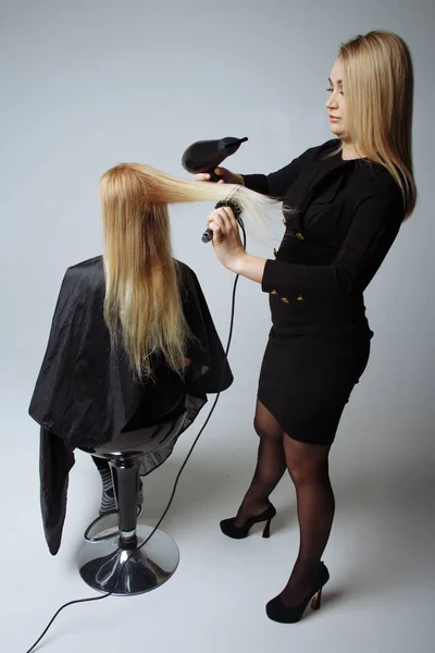 Il parrucchiere asciuga capelli con un asciugacapelli in salone di bellezza — Foto Stock