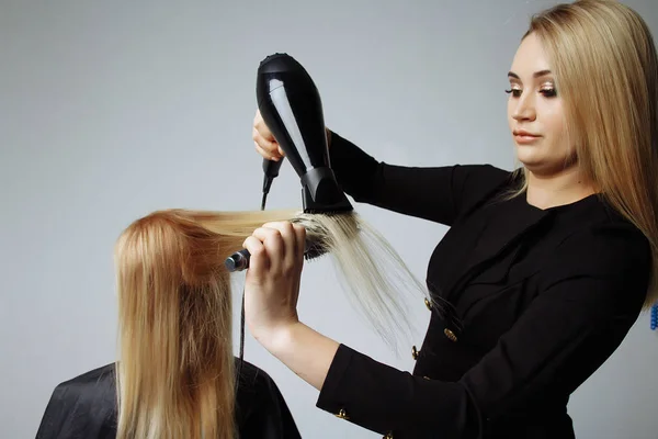 Ritratto di una ragazza Parrucchiere asciuga i capelli con un asciugacapelli nel salone di bellezza — Foto Stock
