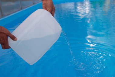 Erkekler eller hafif sıvı plastik bir tank bir havuza su içine dökün. kimyasal su arıtma, alkali dengesi, sağlıksız koşullar. dezenfeksiyon ve yüzme için hazırlık. p için bakım