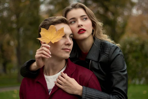 The couple hugs and sadly, the girl hugs the guy from behind and leans a yellow sheet to his face — Stock Photo, Image