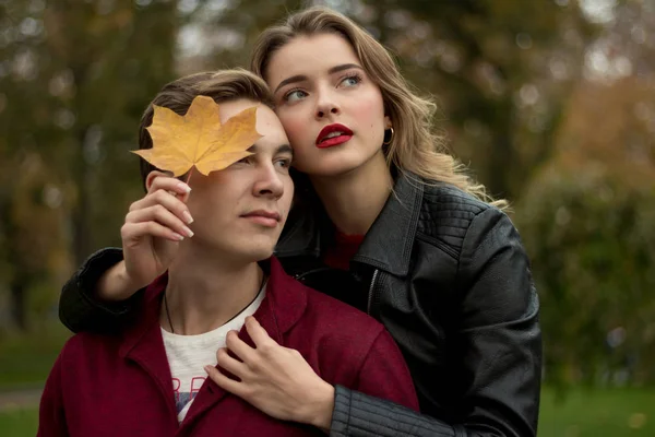 The couple hugs and sadly, the girl hugs the guy from behind and leans a yellow sheet to his face — Stock Photo, Image