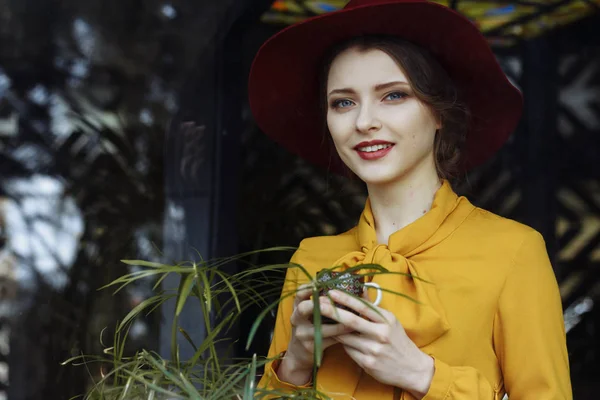 Portrait d'une fille dans un café avec une tasse de café et un chapeau.portrait d'une jeune fille sensuelle portant chapeau et chemisier avec arc. Belle femme brune dans un café tenant une tasse de café — Photo