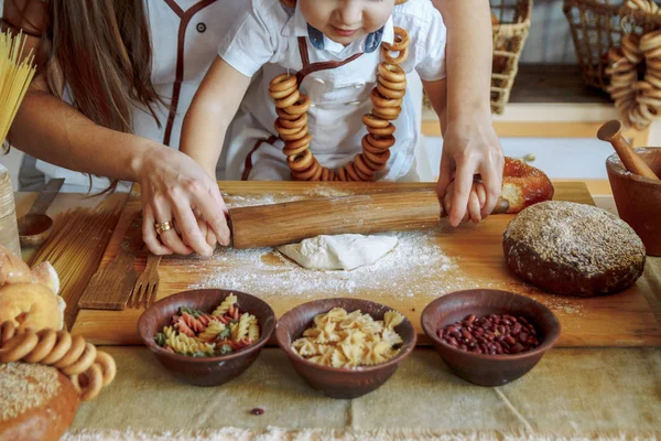 一个孩子和他的母亲在厨房里推出面团, 从面团, 面粉, 面包店, 面包的产品。大师班 — 图库照片