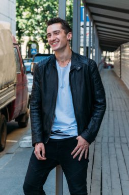 yakışıklı, çekici bir adam, siyah pantolon beyaz T-shirt, siyah, deri ceket, Korkuluk üzerine yaslanmış duran