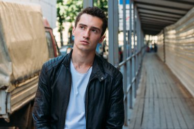 yakışıklı, çekici bir adam, siyah pantolon beyaz T-shirt, siyah, deri ceket, Korkuluk üzerine yaslanmış duran