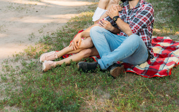 пара сидит на красной клетке на поляне с зеленой травой, летние каникулы, выходные, туристы

