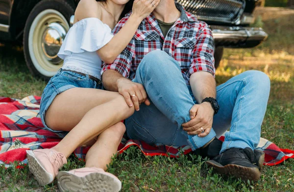 Пара сидит на красной клетке на поляне с зеленой травой, летние каникулы, выходные, туристы целуются, сексуальность — стоковое фото
