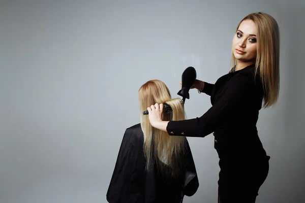 Retrato de una chica Peluquería seca el cabello con un secador de pelo en el salón de belleza —  Fotos de Stock