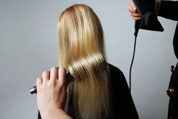 Portret van een meisje Kapper droogt haar met een haardroger in de beauty salon — Stockfoto