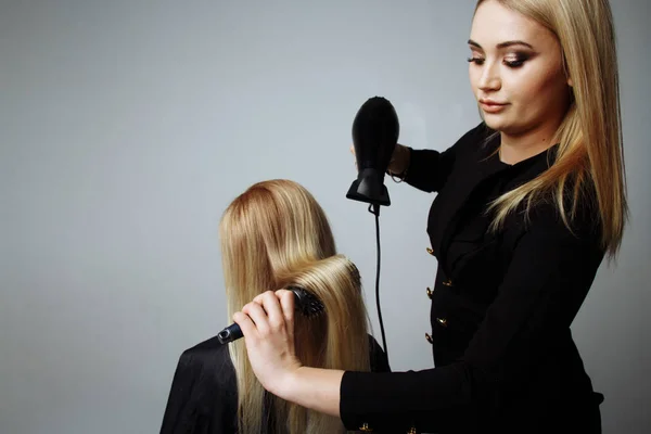 Ritratto di una ragazza Parrucchiere asciuga i capelli con un asciugacapelli nel salone di bellezza — Foto Stock