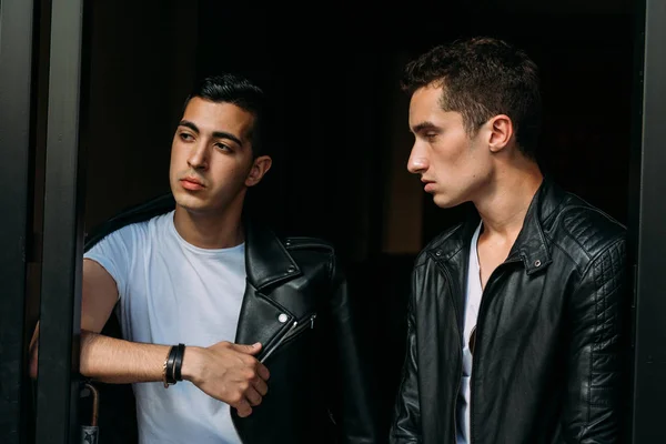 two attractive men are standing nearby, friends, posing, in black jackets and white T-shirts