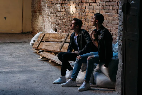 two attractive men are standing nearby, friends, posing, in black jackets and white T-shirts